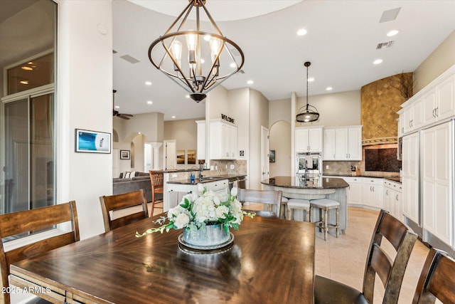 tiled dining space with sink and ceiling fan with notable chandelier