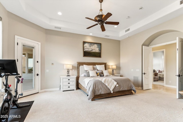 bedroom with access to exterior, ceiling fan, a tray ceiling, and light carpet