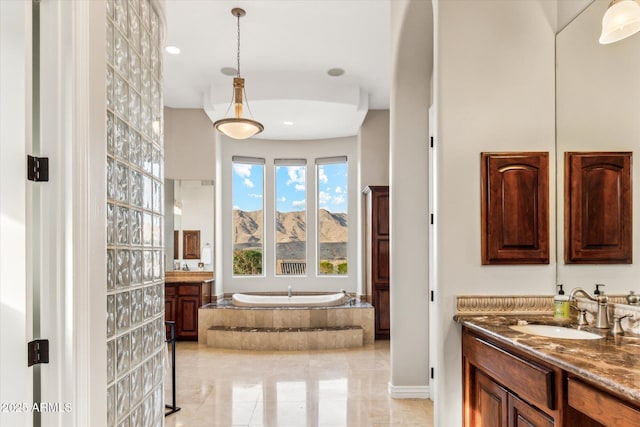 bathroom with vanity, a mountain view, and a relaxing tiled tub