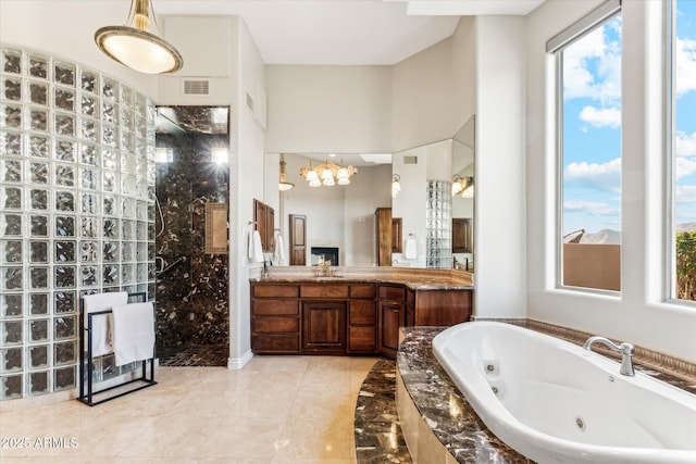 bathroom with vanity, independent shower and bath, and an inviting chandelier