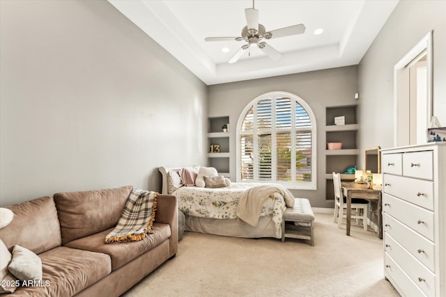 carpeted bedroom featuring a raised ceiling and ceiling fan