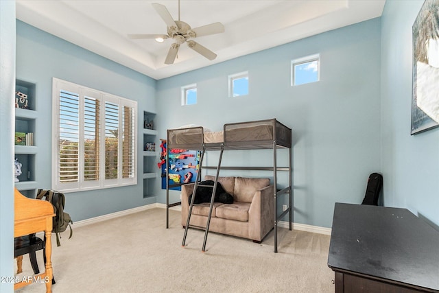 carpeted bedroom with ceiling fan, a raised ceiling, and multiple windows