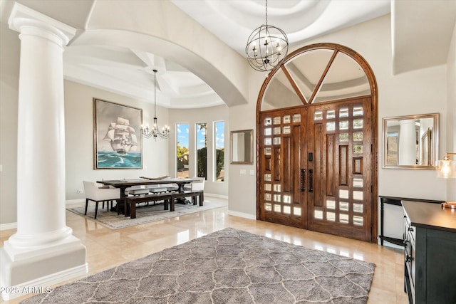 entryway featuring a tray ceiling, decorative columns, a chandelier, and a towering ceiling