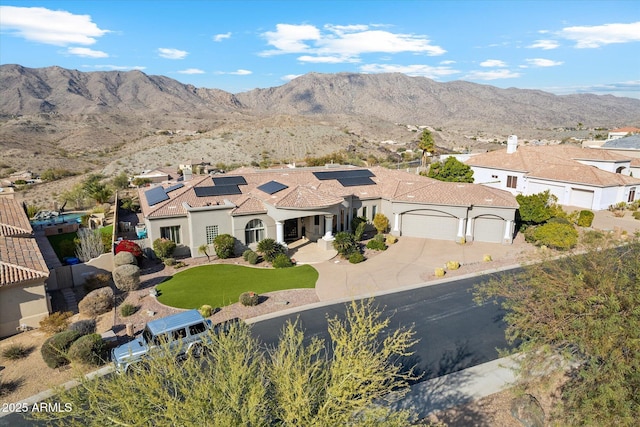 exterior space featuring a garage, a mountain view, a front yard, and solar panels