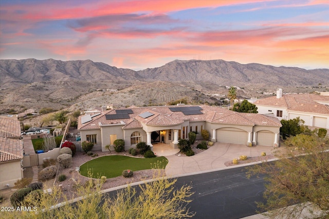 view of front of property with a garage, a mountain view, and solar panels