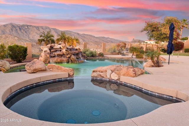 pool at dusk featuring pool water feature and a mountain view