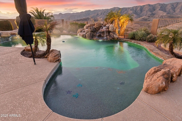 pool at dusk with a mountain view and pool water feature