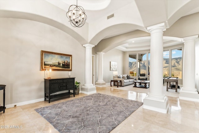 foyer featuring decorative columns, a raised ceiling, and a high ceiling