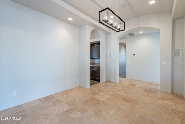 unfurnished room featuring an inviting chandelier