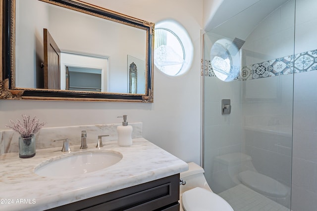 bathroom featuring a tile shower, vanity, and toilet