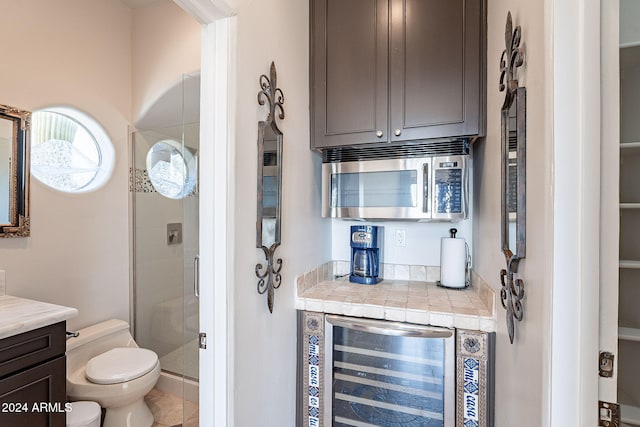 bar featuring tile patterned floors, dark brown cabinets, and wine cooler