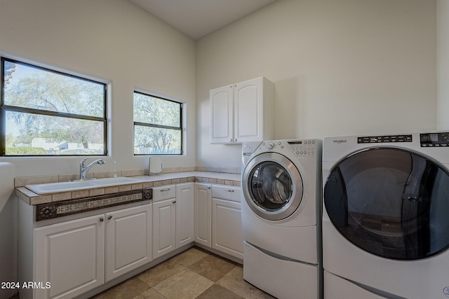 laundry area with cabinets, separate washer and dryer, and sink