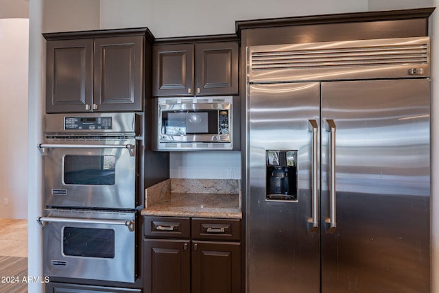 kitchen featuring built in appliances and dark brown cabinetry