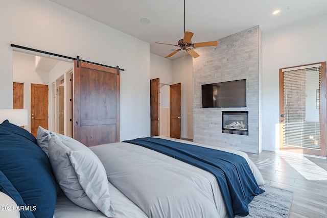 7845 E Dynamite Blvd, Scottsdale, AZ 85266 - bedroom featuring wood finished floors, a fireplace, a barn door, and ceiling fan