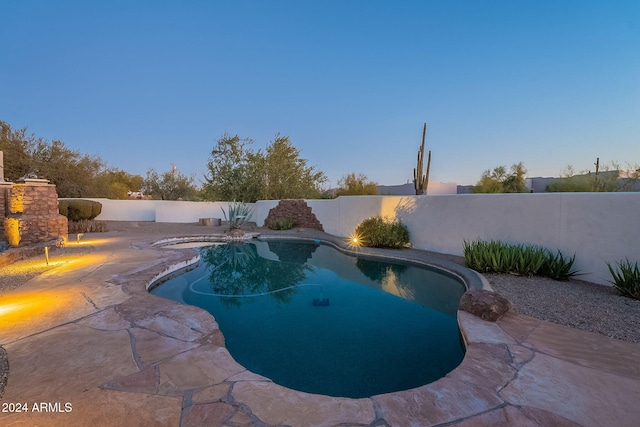 pool at dusk featuring a patio area