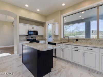 3634 N Desert Oasis, Mesa, AZ 85207 - kitchen featuring appliances with stainless steel finishes, a sink, white cabinets, arched walkways, and light stone counters