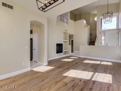 3634 N Desert Oasis, Mesa, AZ 85207 - unfurnished living room with a chandelier, arched walkways, wood finished floors, and baseboards