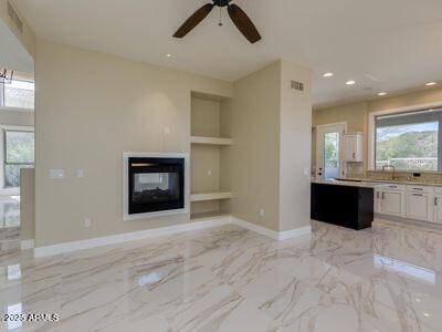 3634 N Desert Oasis, Mesa, AZ 85207 - unfurnished living room with built in features, a multi sided fireplace, ceiling fan, baseboards, and recessed lighting