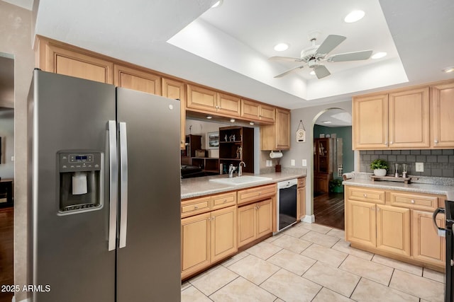 kitchen featuring a raised ceiling, arched walkways, stainless steel fridge, a sink, and dishwashing machine