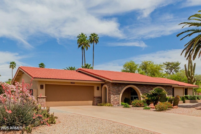view of front of home with concrete driveway, stucco siding, stone siding, an attached garage, and a tiled roof