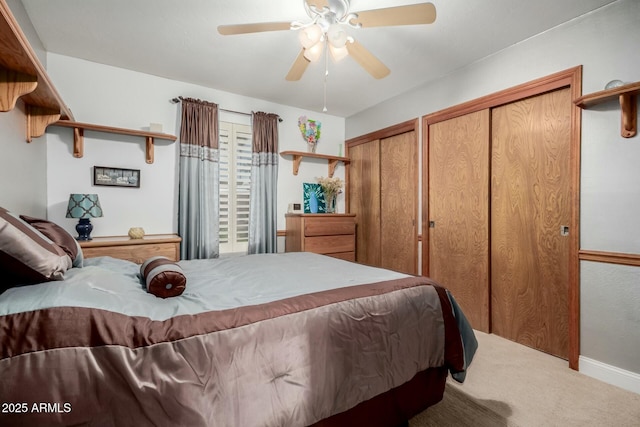 carpeted bedroom with baseboards, a ceiling fan, and two closets