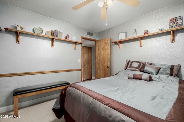 carpeted bedroom featuring visible vents, a ceiling fan, and a textured wall