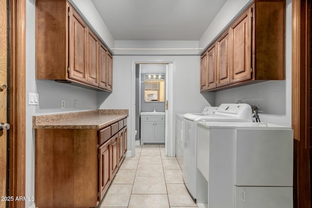 laundry room featuring cabinet space, light tile patterned floors, washer and dryer, and a sink