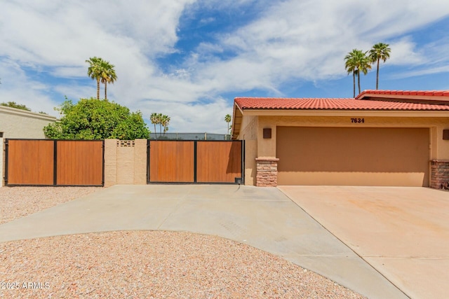mediterranean / spanish home featuring concrete driveway, a garage, stucco siding, and a gate