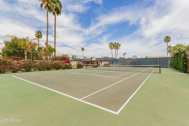 view of tennis court featuring community basketball court and fence