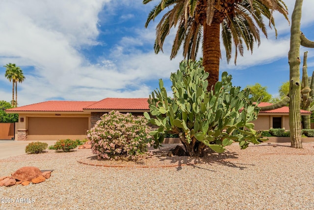 view of front facade with a tiled roof, concrete driveway, a garage, and stucco siding