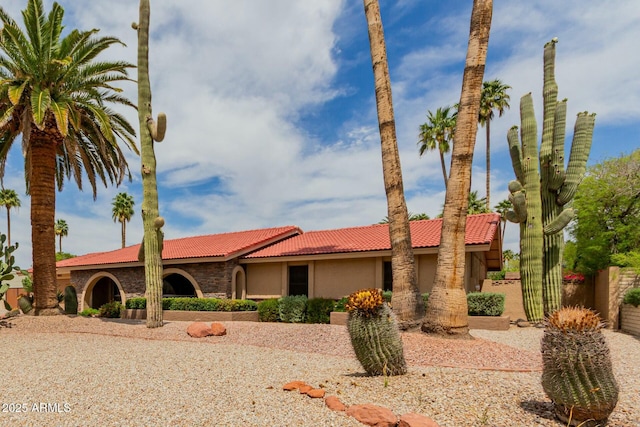 view of front of home with stucco siding, stone siding, and a tile roof