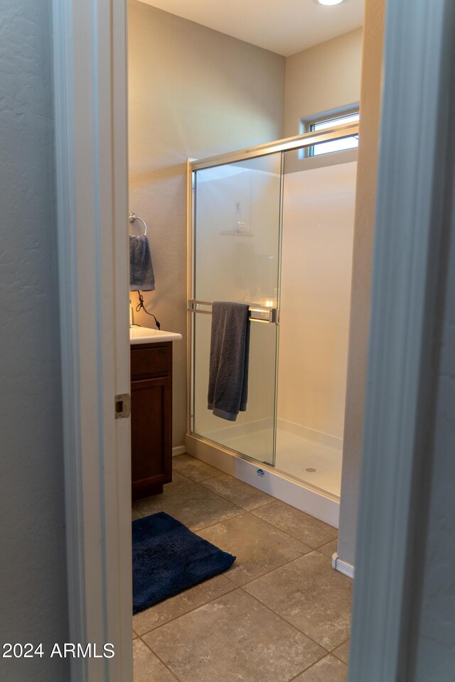 bathroom featuring vanity, tile patterned floors, and a shower with shower door