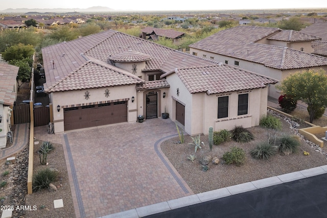 mediterranean / spanish-style house with a garage, stucco siding, driveway, and a tile roof