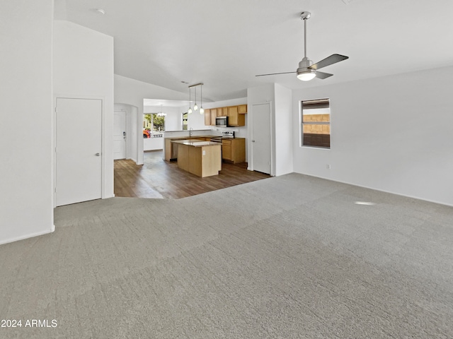 unfurnished living room with dark wood-type flooring, ceiling fan, sink, and vaulted ceiling