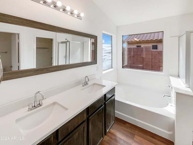 bathroom featuring vanity, lofted ceiling, hardwood / wood-style floors, and separate shower and tub