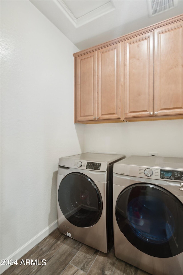 laundry area featuring cabinets, washer and clothes dryer, and dark wood-type flooring