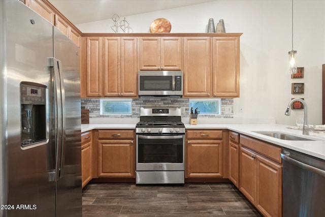 kitchen featuring lofted ceiling, backsplash, hanging light fixtures, sink, and appliances with stainless steel finishes