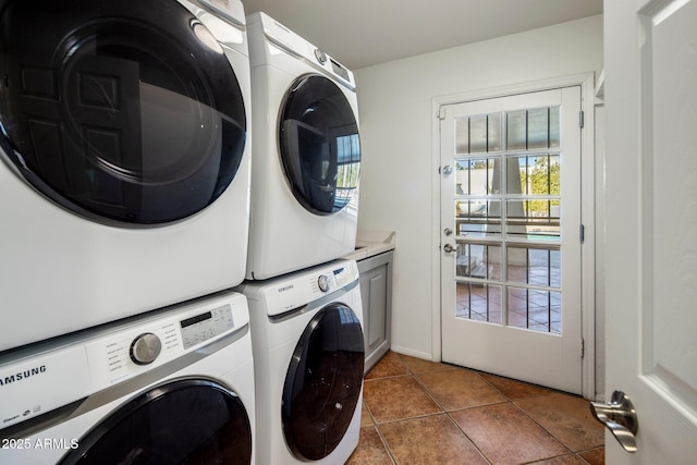 laundry room with cabinets, stacked washer and clothes dryer, and dark tile patterned floors