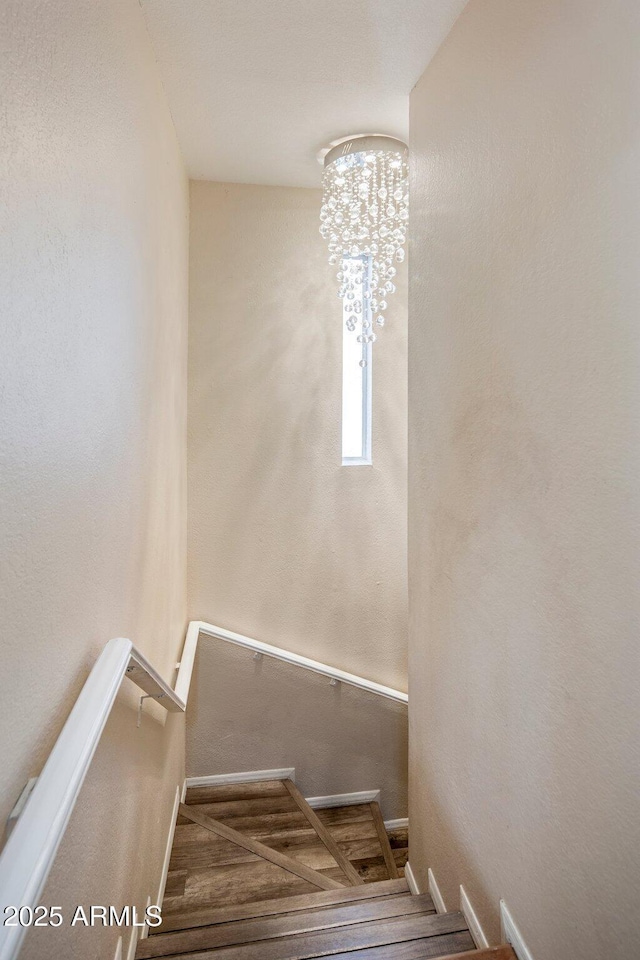 stairway with a notable chandelier