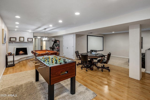 rec room with pool table, a fireplace, and light hardwood / wood-style floors