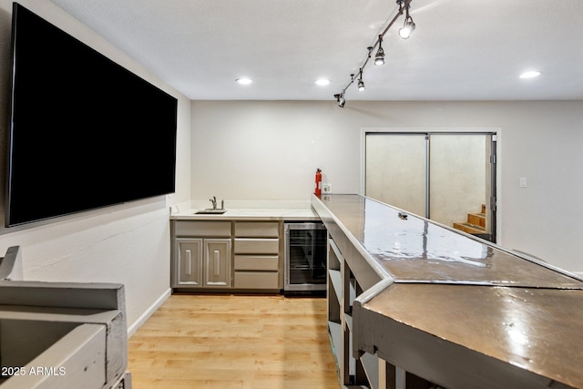 kitchen featuring gray cabinets, rail lighting, beverage cooler, and light hardwood / wood-style flooring