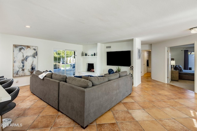 tiled living room featuring a large fireplace and a textured ceiling