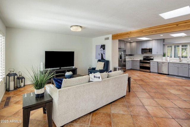 living room with sink, a skylight, and light tile patterned flooring