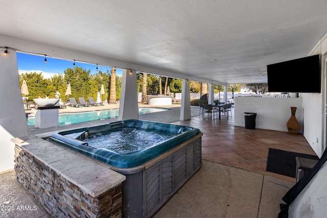 view of patio / terrace with a swimming pool with hot tub