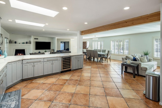 kitchen featuring wine cooler, beam ceiling, gray cabinets, and light tile patterned floors