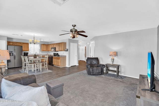2412 W Camp River Rd, San Tan Valley, AZ 85144 - living area with dark wood-style floors, dark carpet, visible vents, baseboards, and ceiling fan with notable chandelier