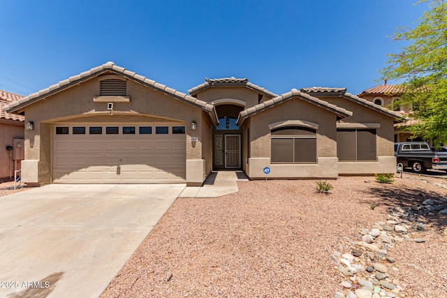 mediterranean / spanish-style home with concrete driveway, stucco siding, an attached garage, and a tiled roof