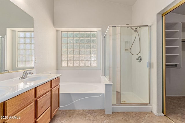 full bathroom featuring a shower stall, a bath, double vanity, and a spacious closet