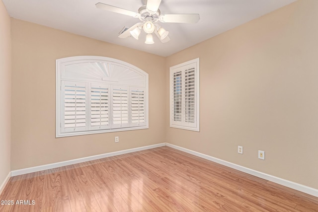 empty room with wood finished floors, baseboards, and a ceiling fan