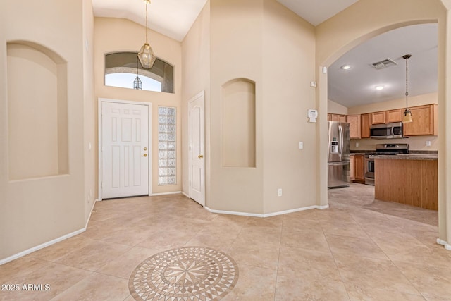 entrance foyer featuring arched walkways, baseboards, light tile patterned floors, and high vaulted ceiling